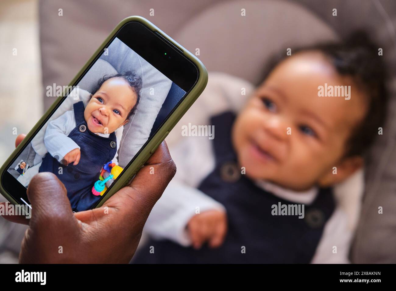 A baby is smiling at the camera while her mom is taking a photo. Stock Photo
