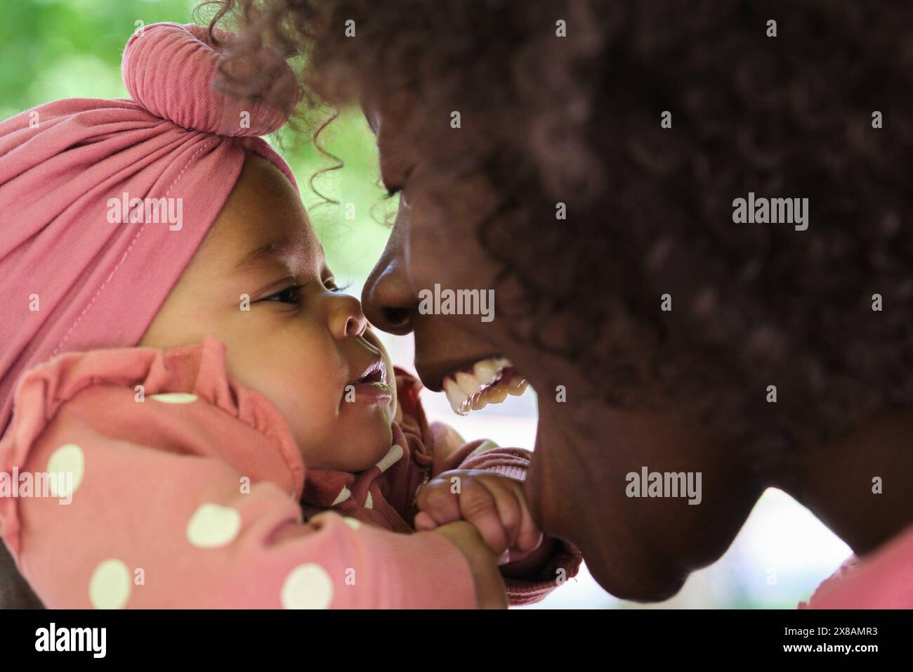 African woman playing with her baby girl in a park. Stock Photo