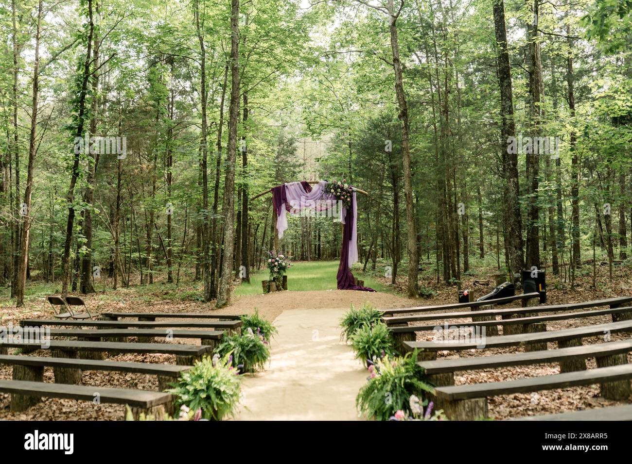Outdoor wedding ceremony setup in a forest with a purple-draped altar Stock Photo