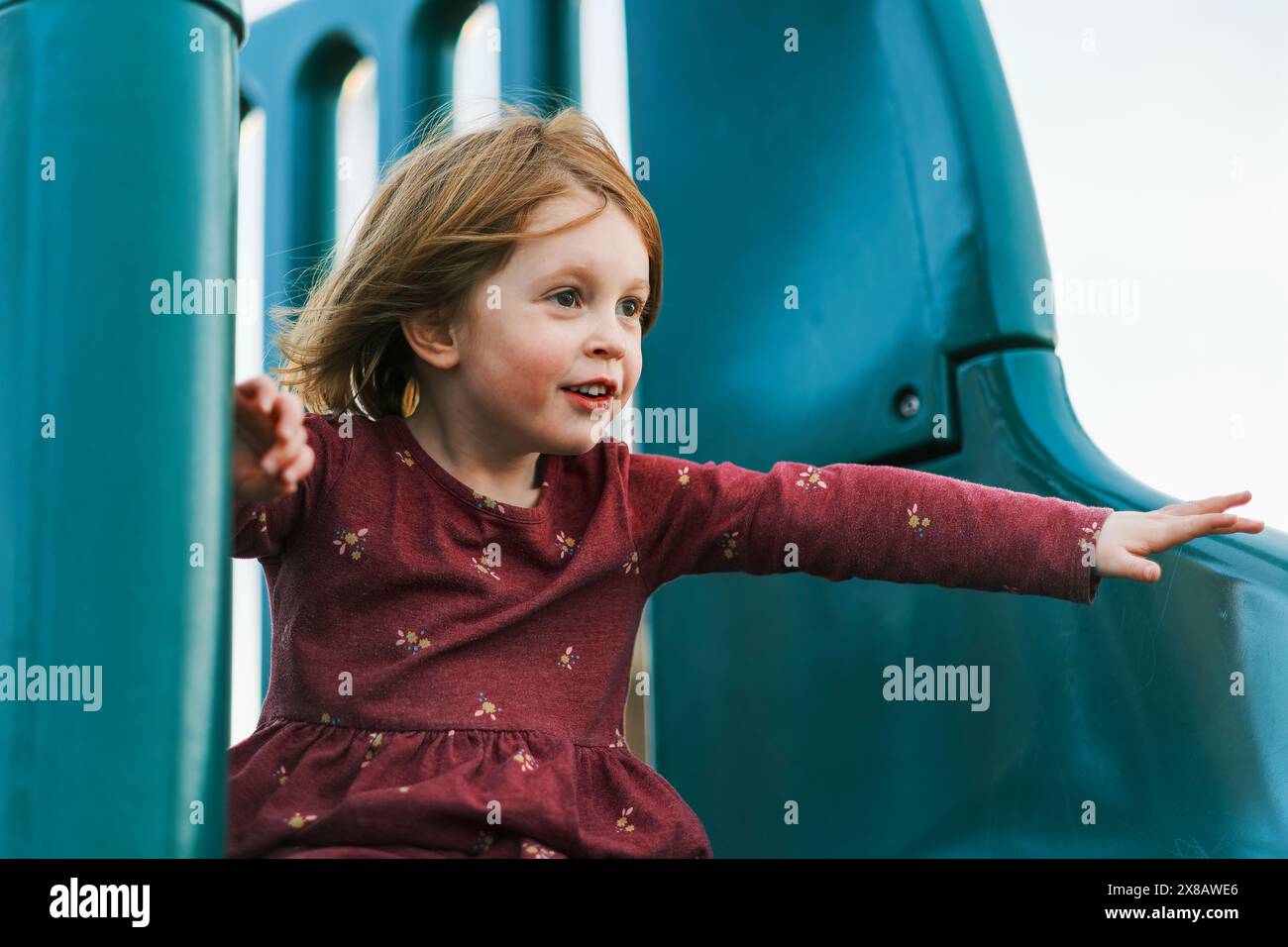 Little girl joyfully playing on a slide at the playground Stock Photo ...