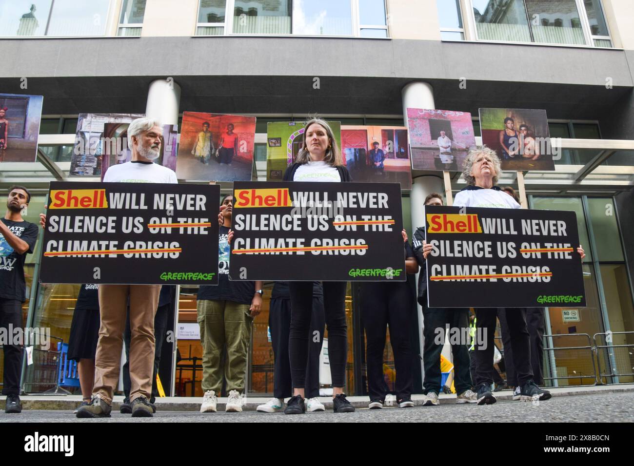 London, UK. 24th May 2024. Greenpeace activists stand with placards and photos by Gideon Mendel outside the Rolls Building as fossil fuel giant Shell takes the environmental organisation to court in response to a protest in 2023, when Greenpeace activists occupied a moving oil platform. Credit: Vuk Valcic/Alamy Live News Stock Photo