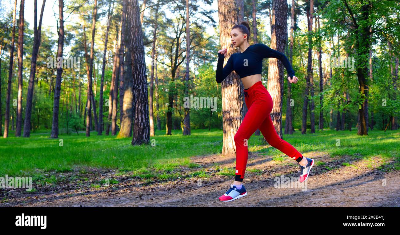A young woman is running through the park in a sports suit. Stock Photo
