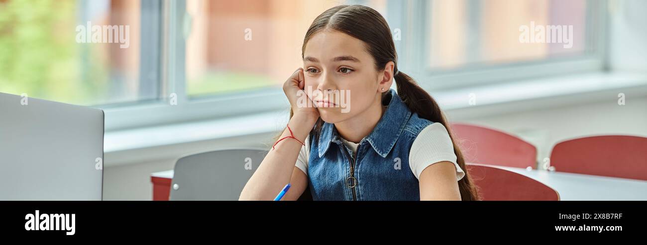 A bored girl sits at a desk, and looking away in classroom Stock Photo ...