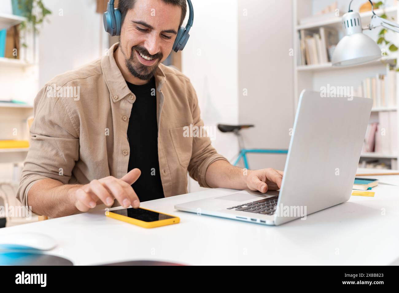 Smiling business man working on laptop at home office. Young student using computer remote studying Stock Photo