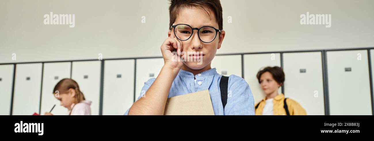 A schoolboy in a blue shirt stands amidst rows of lockers in a school hallway. Stock Photo