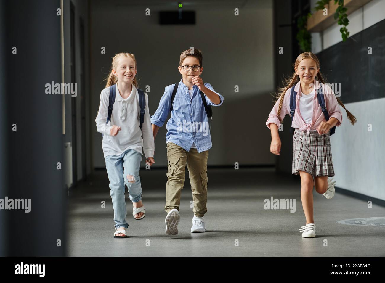 group of young children joyfully walking down a bright hallway Stock Photo