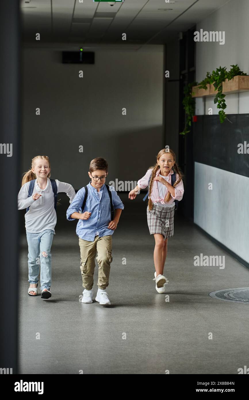 A group of young children laughing and running through a hallway, filled with excitement and energy. Stock Photo