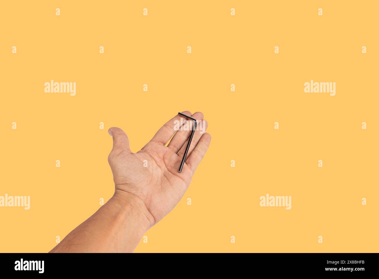 Black male hand holding an allen key isolated on yellow background ...