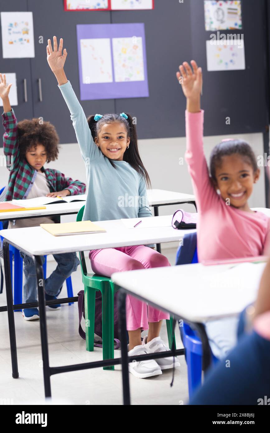 In school, diverse family with two young daughters and a son raising hands in the classroom Stock Photo