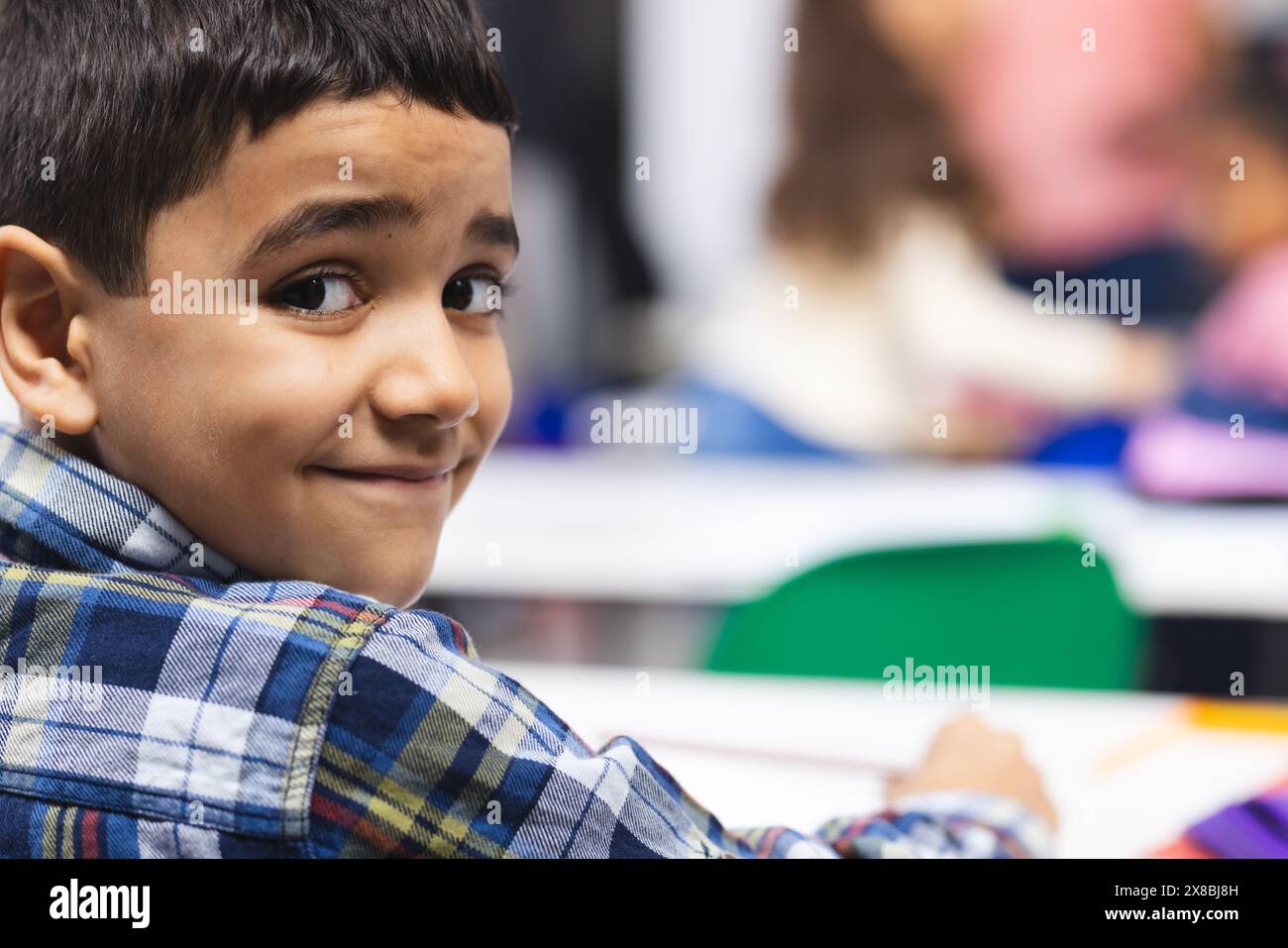 In school, young biracial boy with dark hair is smiling at camera with ...