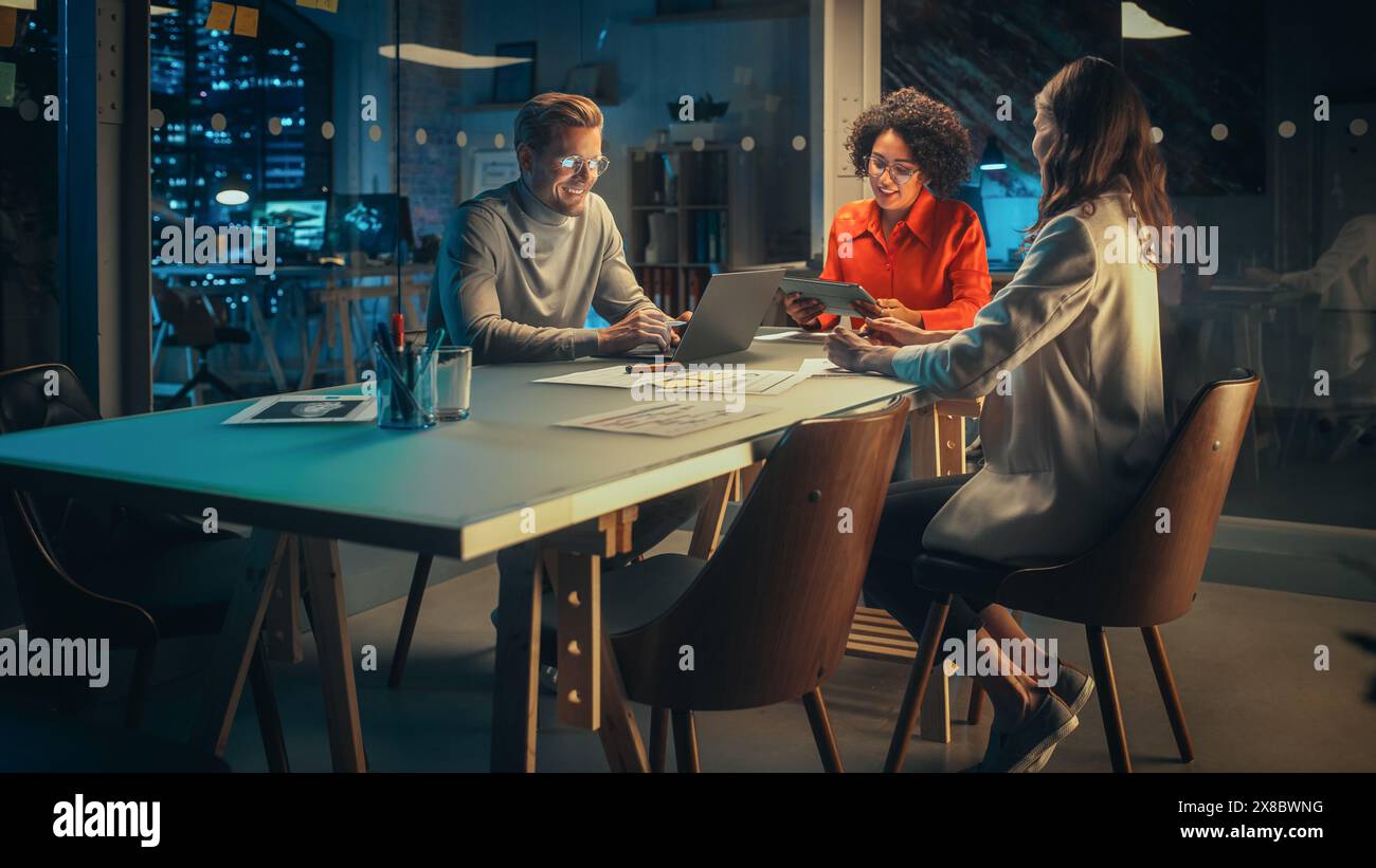 Positive Group of Managers Having a Team Meeting Long After Work Hours in the Night. Inspired Colleagues Discussing Annual Financial and Marketing Reports. Teamwork in Creative Office. Stock Photo