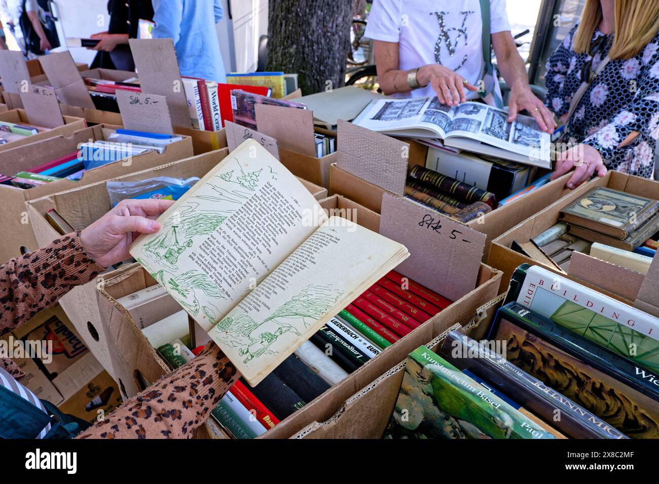 Sammler und Jäger. Am Flohmarkt werden die Kisten mit den antiquarischen Büchern fleissig durchstöbert. Salzburg Salzburg Österreich *** Collectors and hunters At the flea market, the boxes of antiquarian books are rummaged through diligently Salzburg Salzburg Austria Copyright: xRolfxPossx Stock Photo