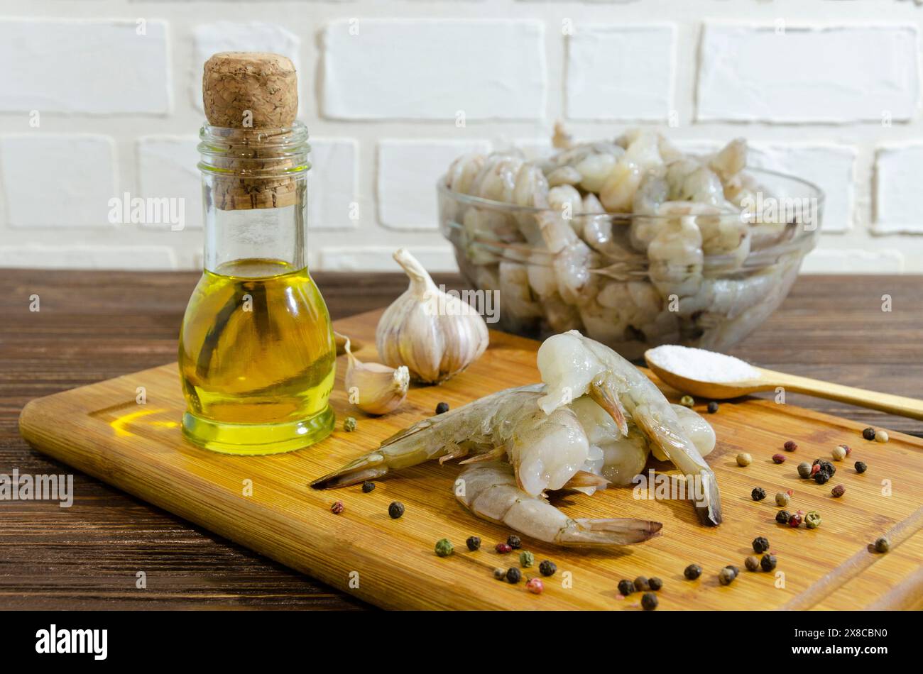 Raw shrimp on a cutting board with olive oil, spices and garlic. Stock Photo