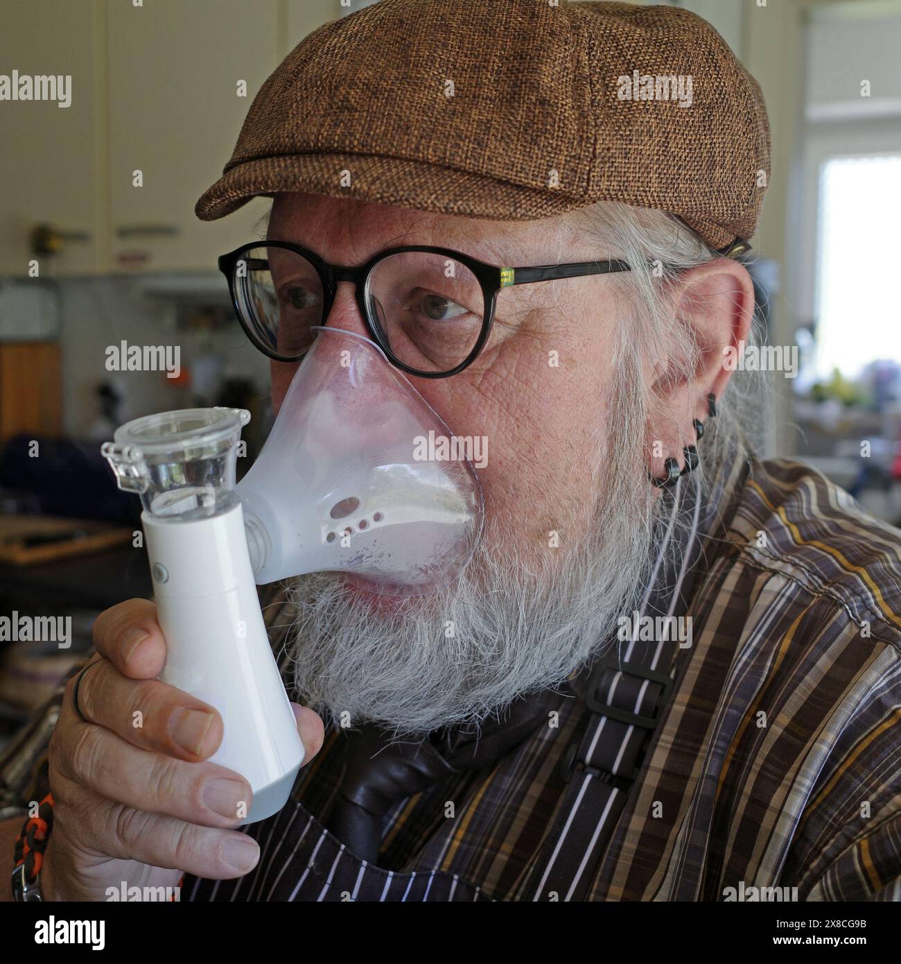 Senior man using a nebulizer to cure throat problems. Stock Photo
