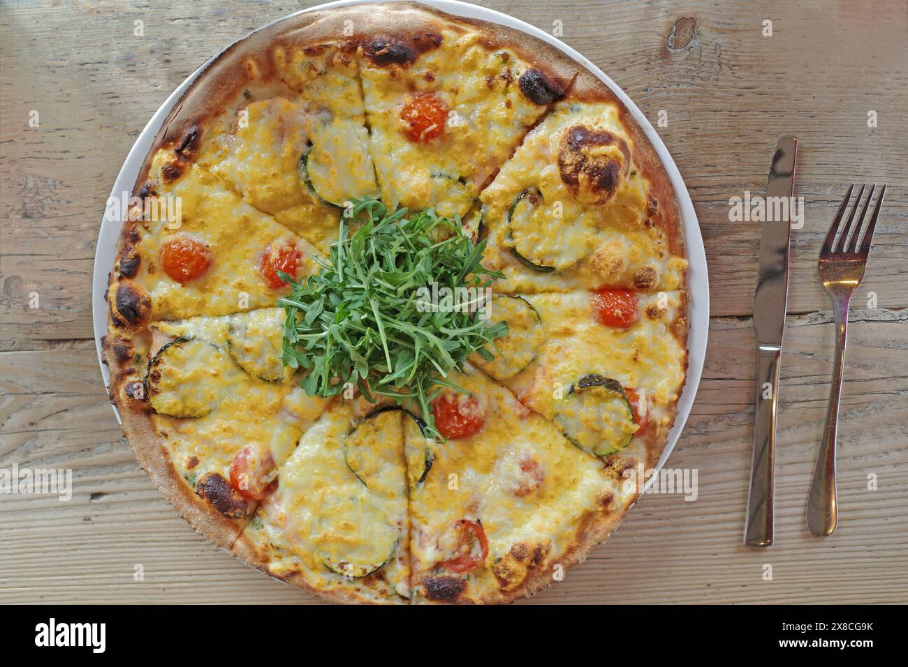 Pizza with arugula, zucchini, mini tomatoes, cheese and salmon Stock Photo