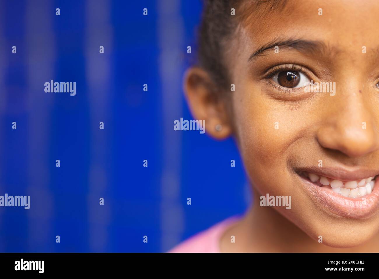 In school, young biracial girl with a bright smile is looking happy with copy space Stock Photo