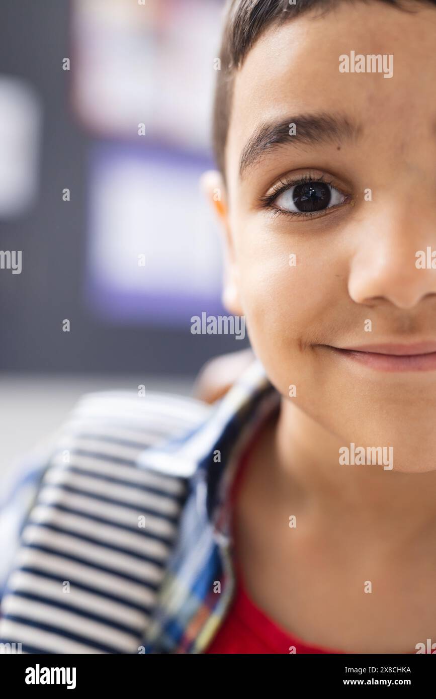 In school, young biracial boy with a striped shirt is smiling in the ...