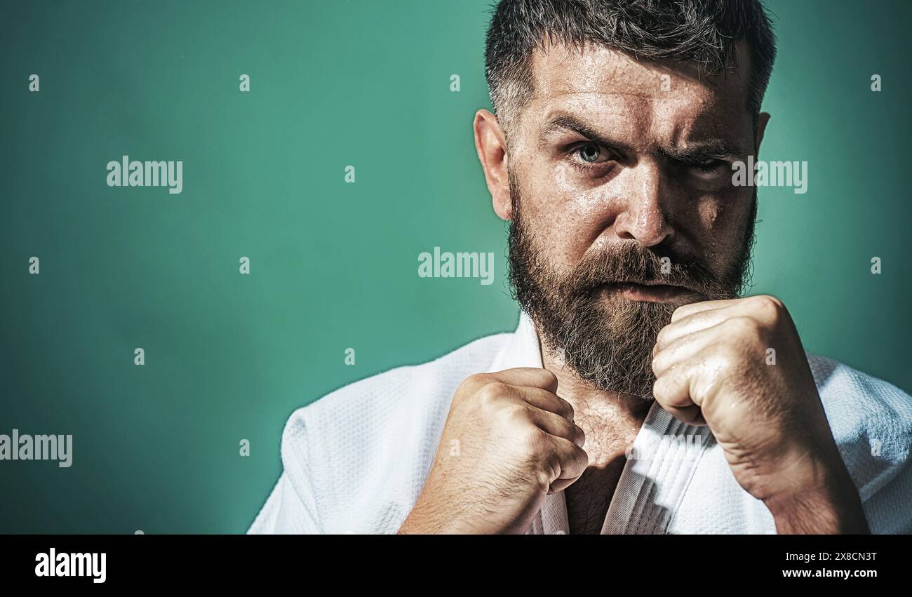 Serious bearded man in kimono in fighting position. Karate fighter preparing for competition. Muscular male ready for karate training. Strong martial Stock Photo