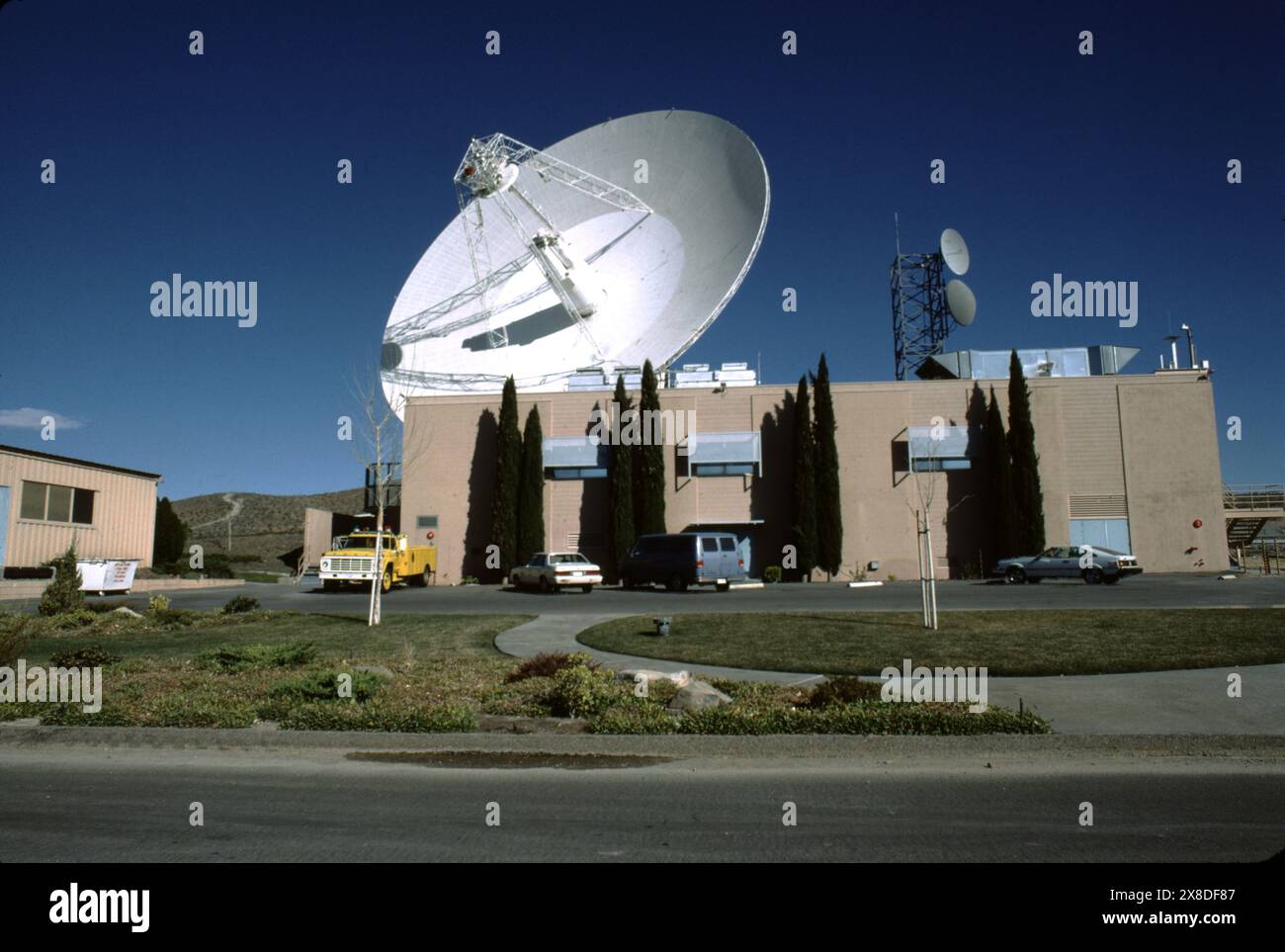 Fort Irwin, CA., U.S.A. circa 1984.  The Goldstone Deep Space Communications Complex (GDSCC), commonly called the Goldstone Observatory, located in Fort Irwin in the U.S. state of California. Operated by NASA's Jet Propulsion Laboratory (JPL), to track and communicate with interplanetary space missions. It is named after Goldstone, California, a nearby gold-mining ghost town.   The largest, a 70-meter (230 ft) Cassegrain antenna, is used for communication with space missions to the outer planets, such as the Voyager spacecraft. Stock Photo