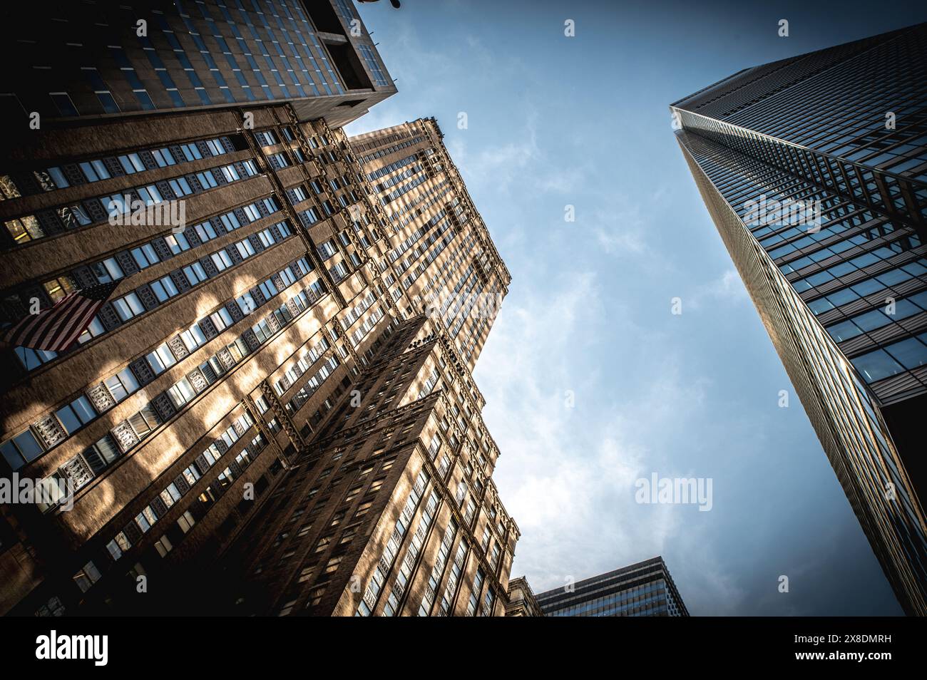 NYC giants reach for the sky! Towering Manhattan buildings dwarf pedestrians on bustling streets. Classic scene for travel and urban life content. Stock Photo