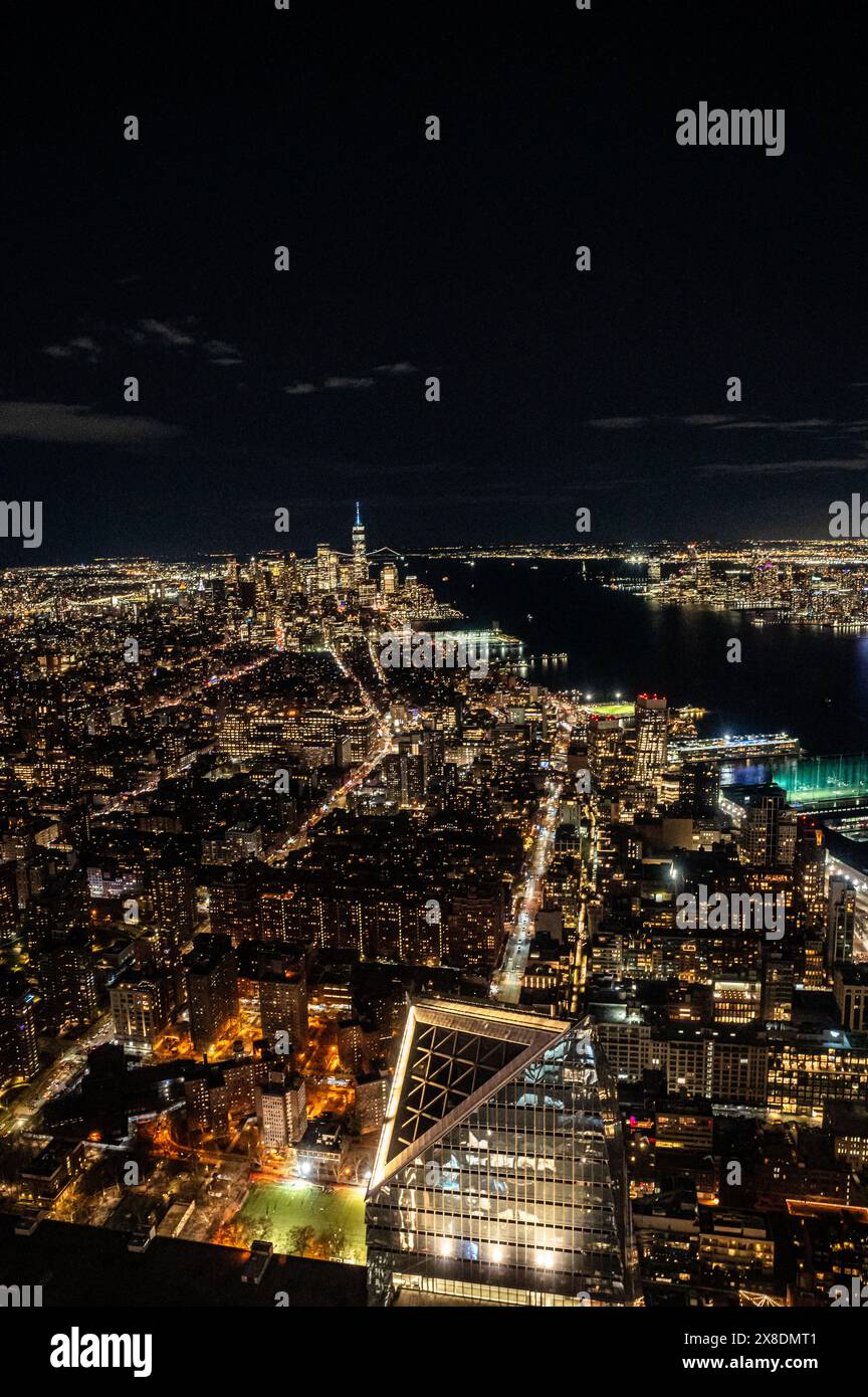 Manhattan's night skyline from a daring perspective from above. Towering giants pierce the clouds, offering a unique vantage point for travel. Stock Photo