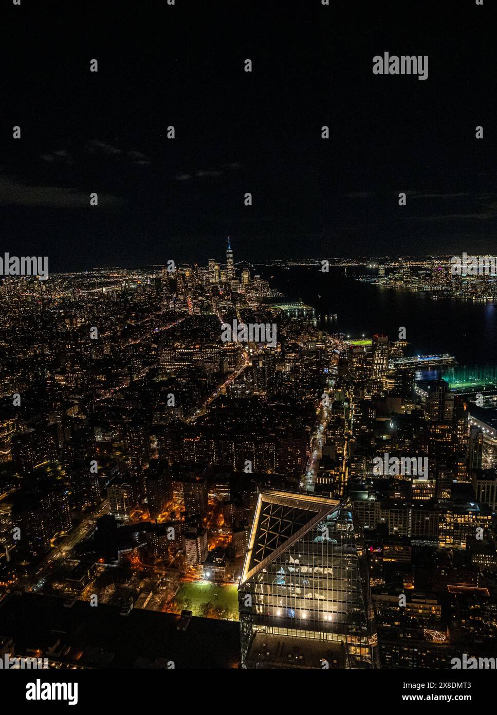 Manhattan's night skyline from a daring perspective from above. Towering giants pierce the clouds, offering a unique vantage point for travel. Stock Photo
