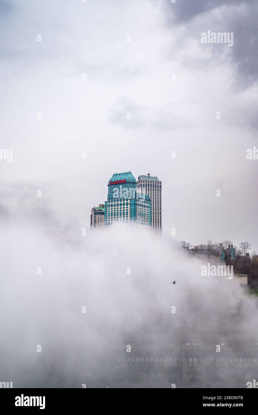 Canadian side of Niagara Falls shrouded in mist. Imposing buildings peek through the clouds, creating an air of mystery. Ideal for travel landscape. Stock Photo