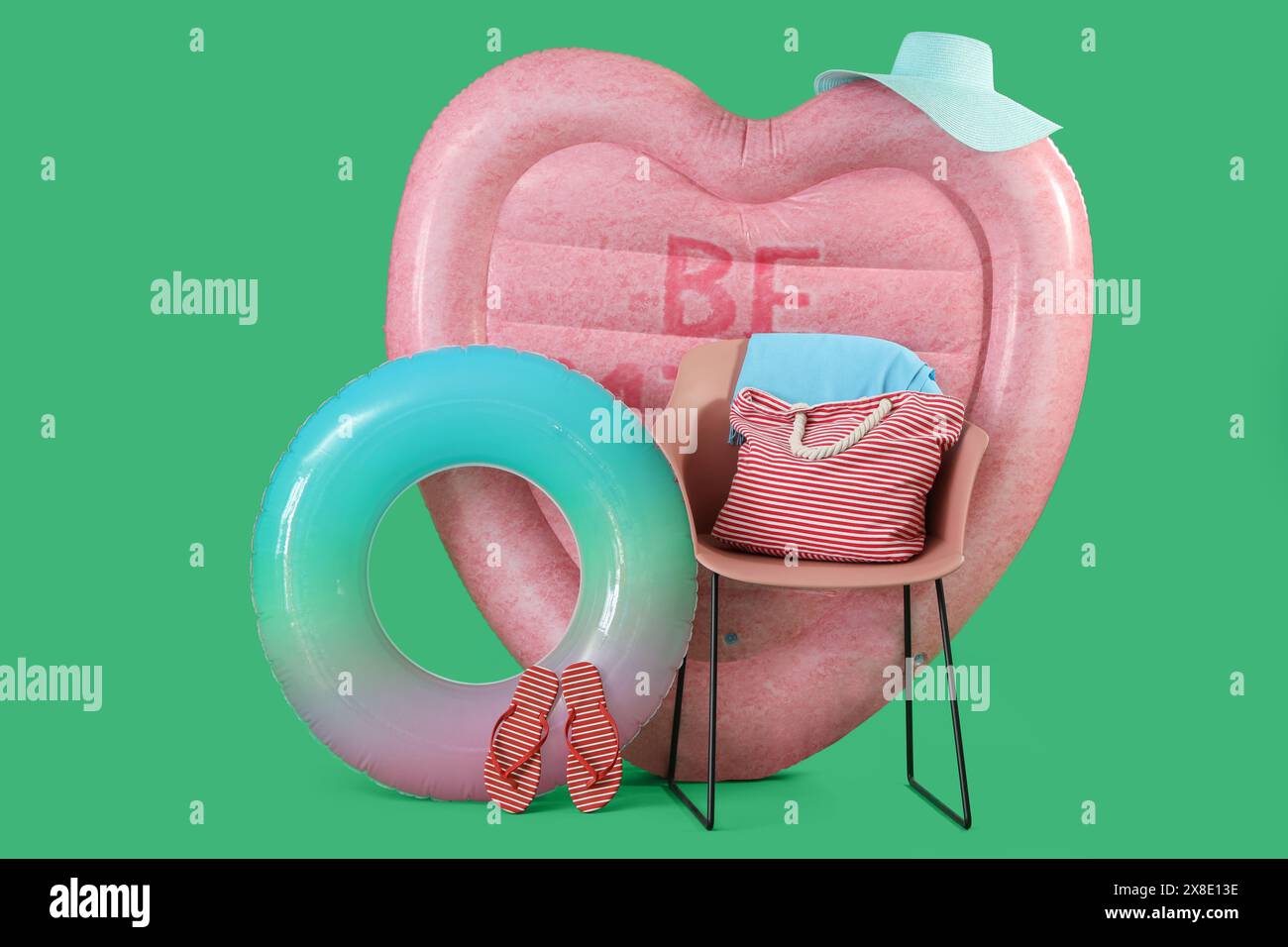 Swimming mattress in shape of heart, inflatable ring and chair with bag on green background Stock Photo