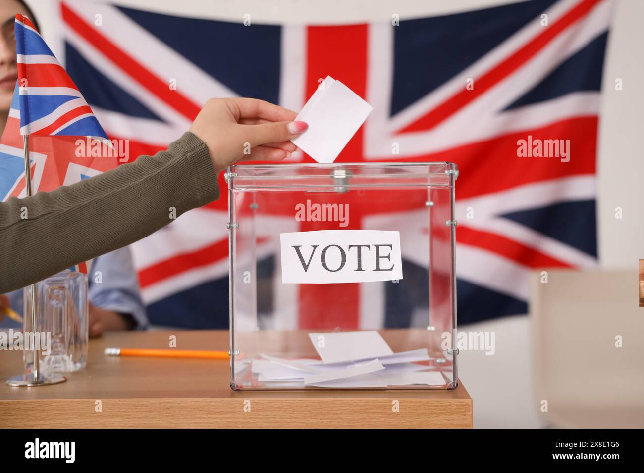 Voting young woman near ballot box with UK flag at polling station, closeup Stock Photo