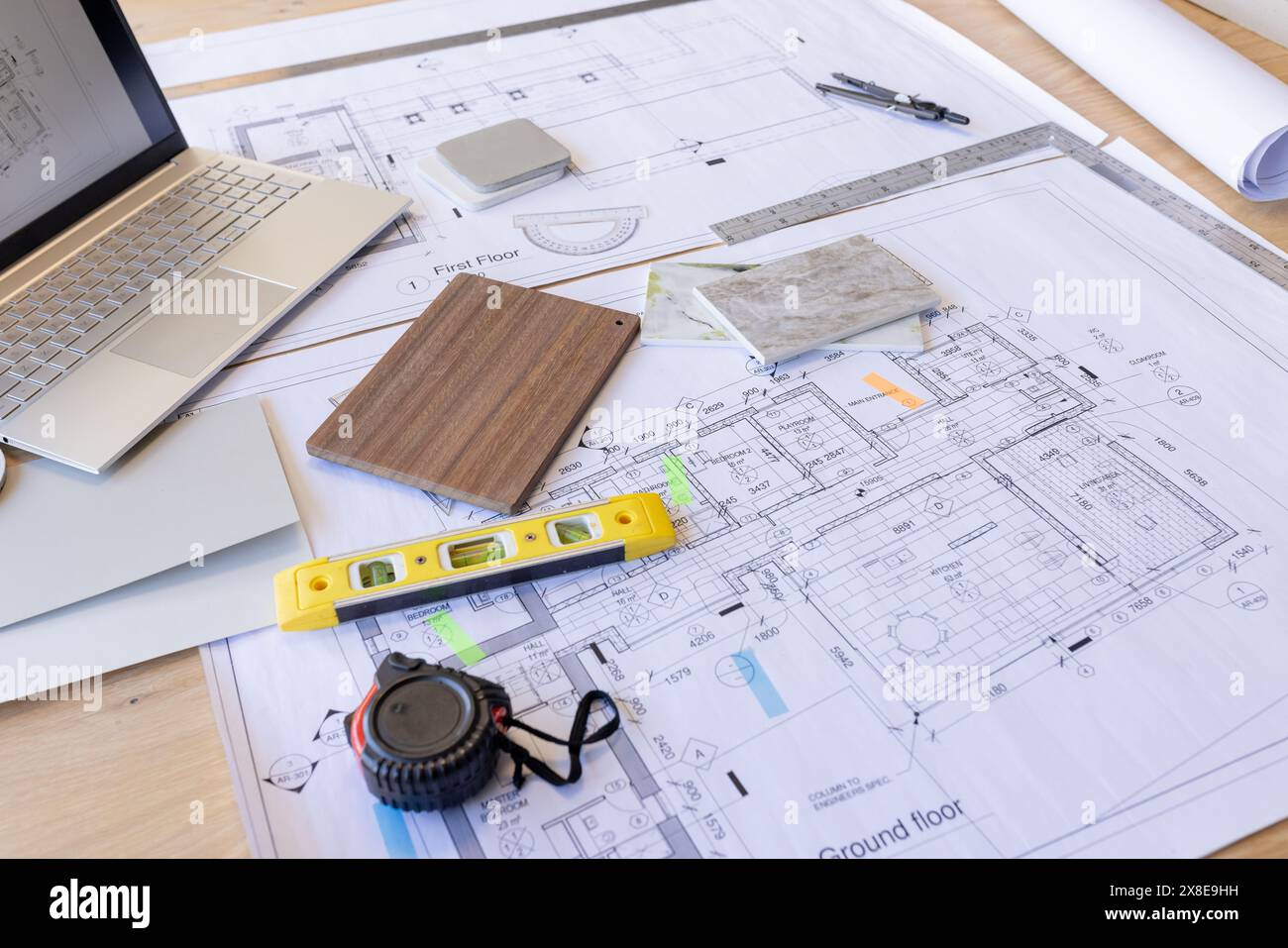 Architectural plans and tools spread out on desk, showing detailed building layouts Stock Photo