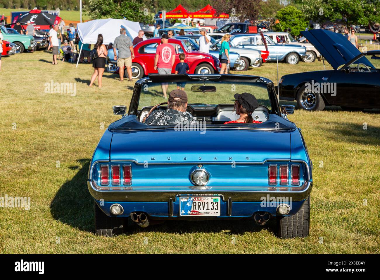 A couple in a blue 1967 Ford Mustang convertible arrives at car show at