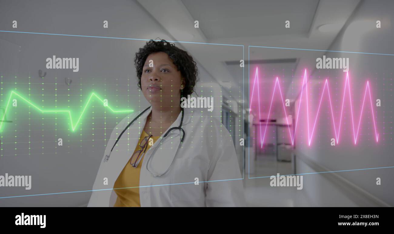 Image of heart rate monitor over african american female doctor walking in corridor at hospital Stock Photo