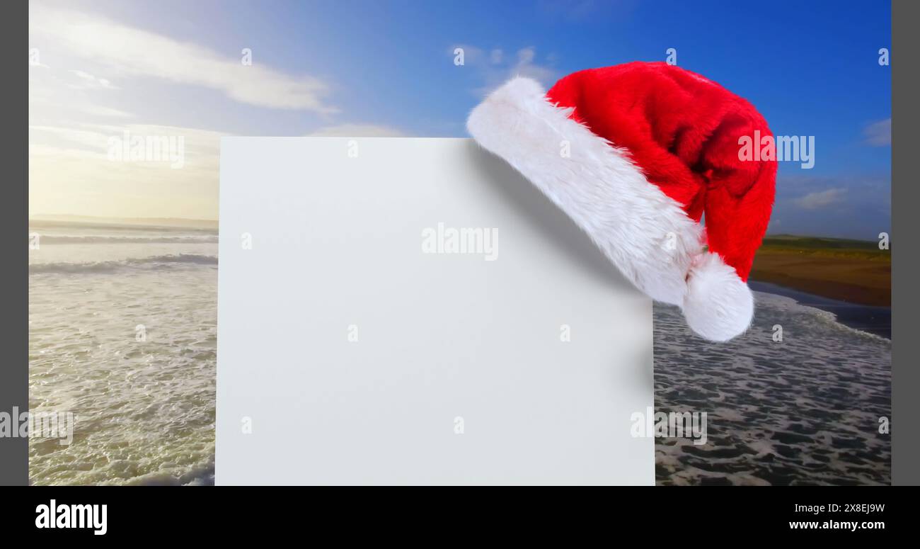 Digital composite of Santa hat with white card and sea Stock Photo
