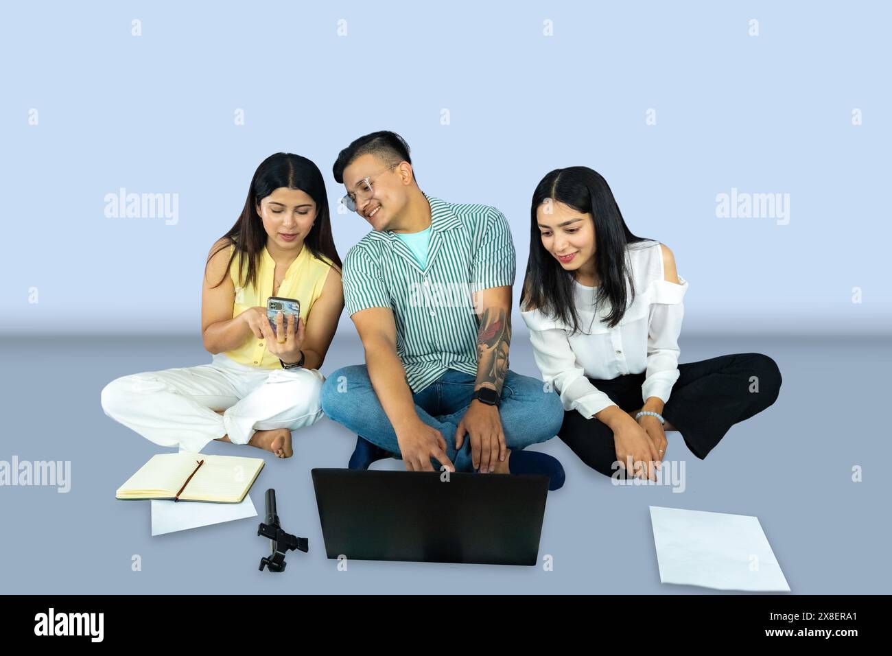 A group of copywriter friends with notepad, mobile phone, laptop giving gestures expresions and working together joyfully Stock Photo