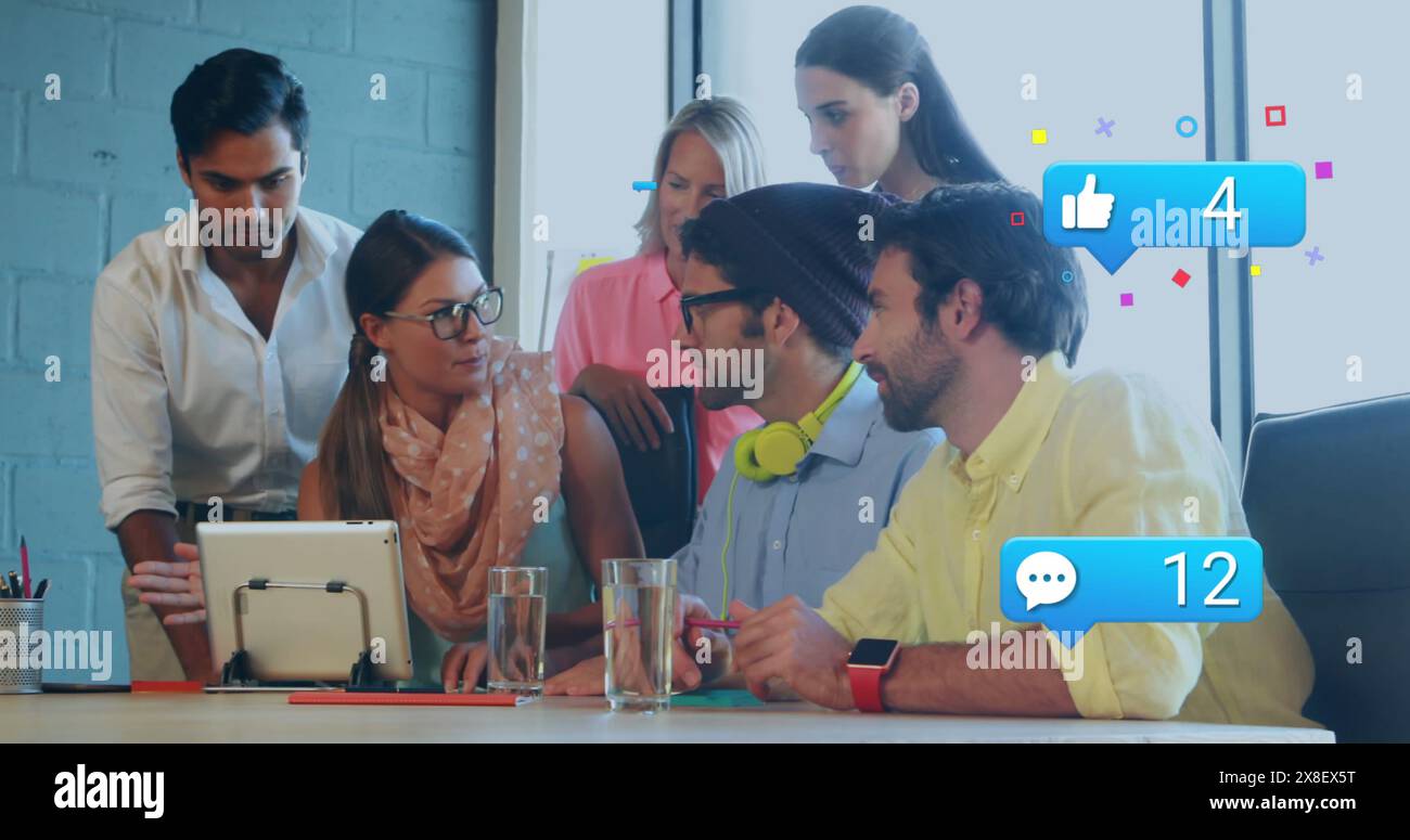 Image of social media icons over diverse colleagues discussing together at office Stock Photo