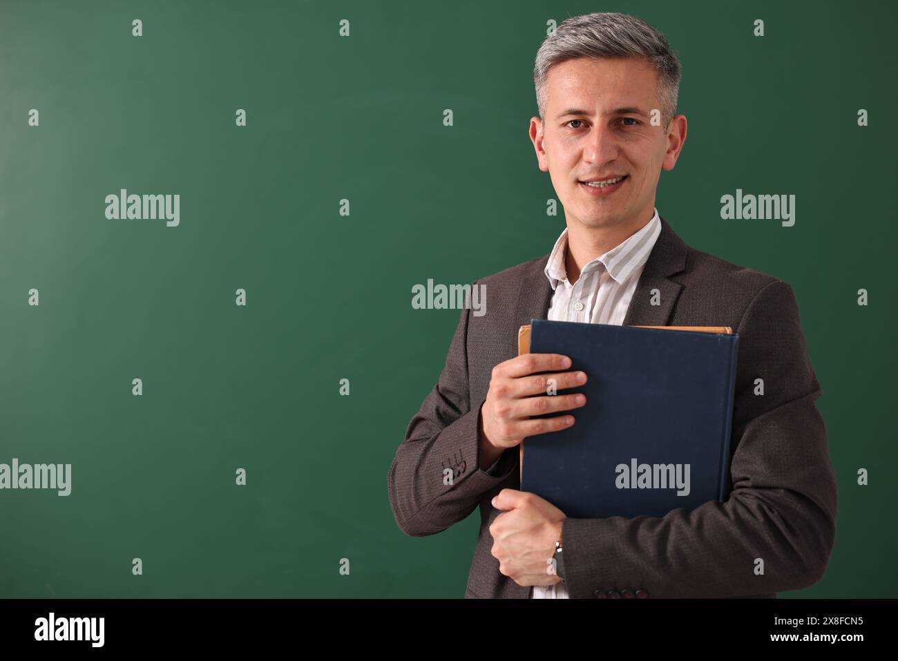 Teacher with notebooks near chalkboard, space for text Stock Photo