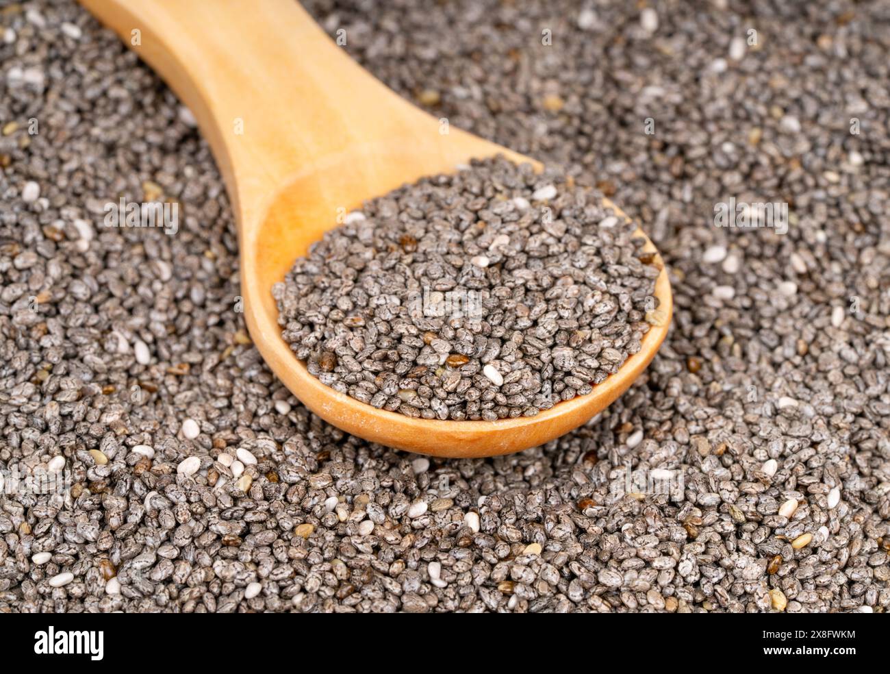 Scattered chia seeds with wooden spoon close up Stock Photo