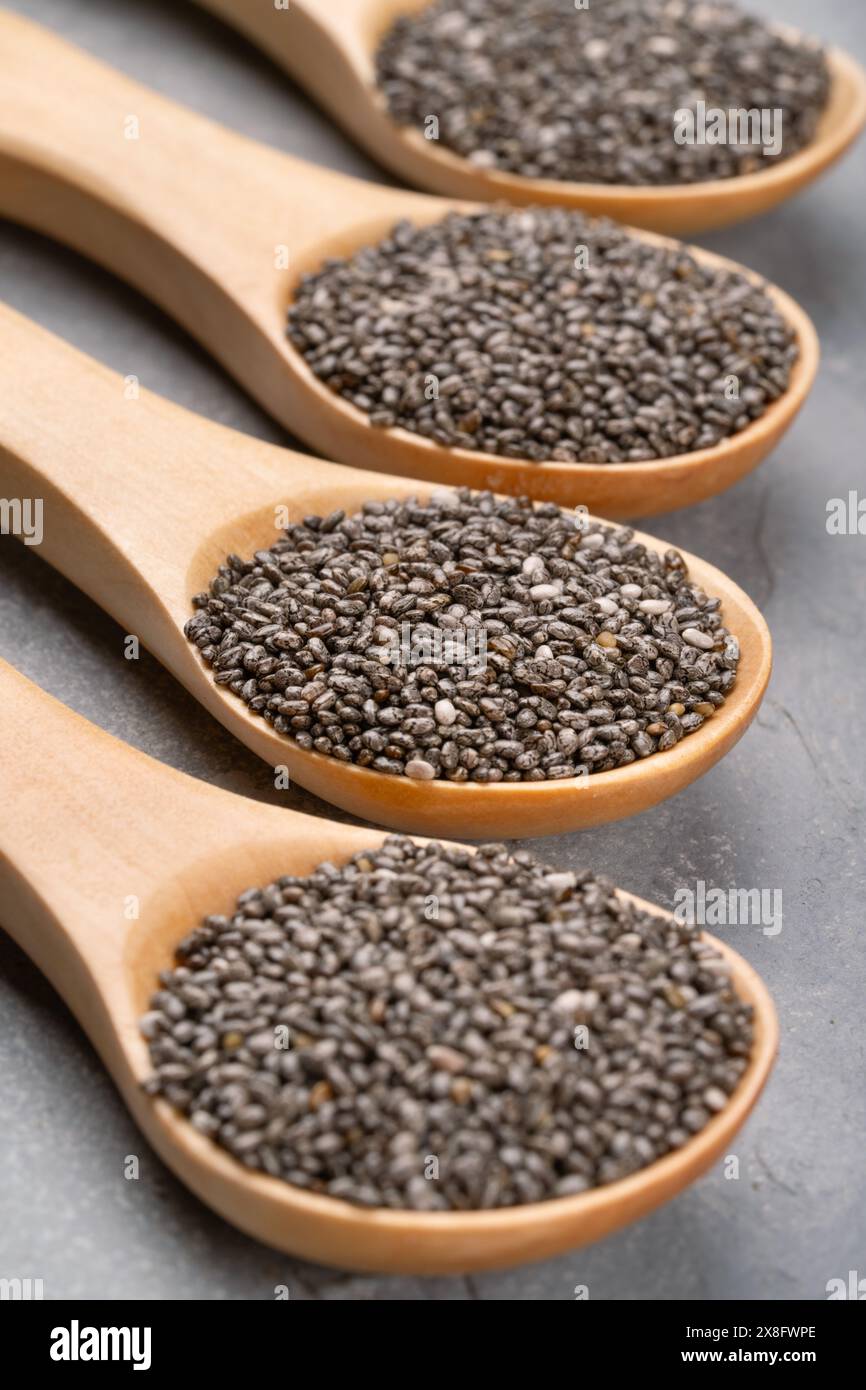 Four wooden spoons full of chia seeds close-up on concrete background Stock Photo