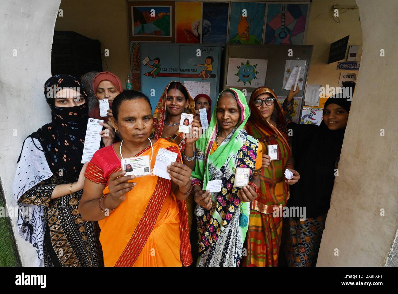 New Delhi, India. 25th May, 2024. Voters show their voting ID cards and finger marked with indelible ink after casting their vote at a polling station in East Delhi for the ongoing Parliamentary Election. (Photo by Sondeep Shankar/Pacific Press) Credit: Pacific Press Media Production Corp./Alamy Live News Stock Photo