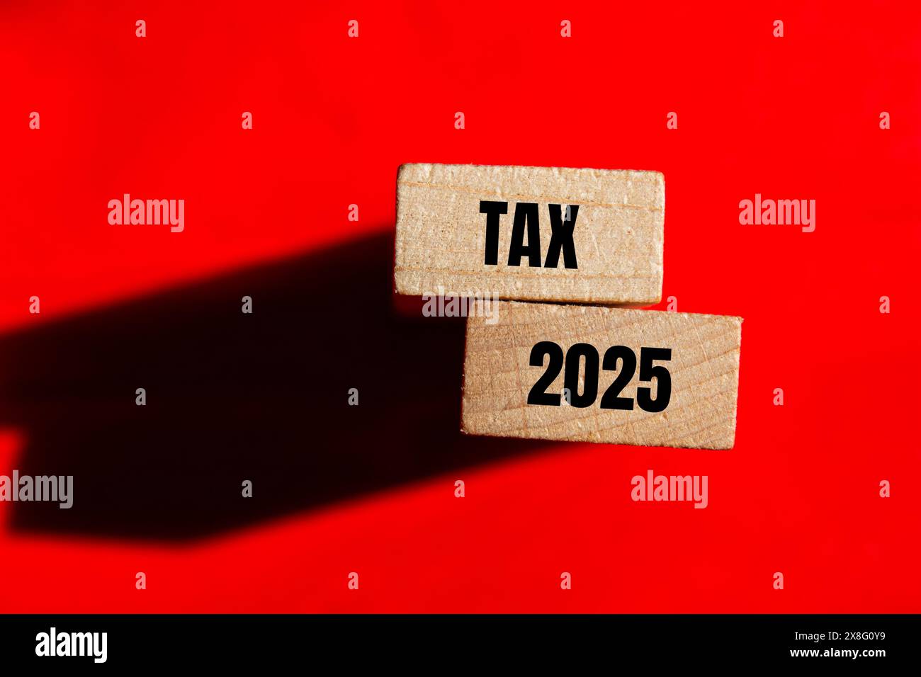 Tax 2025 words written on wooden blocks with red background. Conceptual