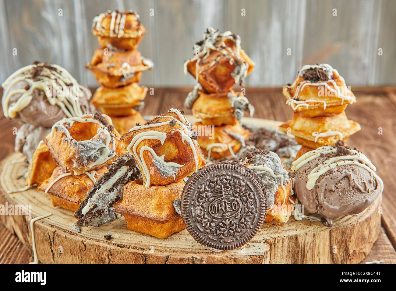 A delicious assortment of donuts, a popular baked good and staple food in American cuisine, is stacked on a wooden table. These sweet confectioneries Stock Photo