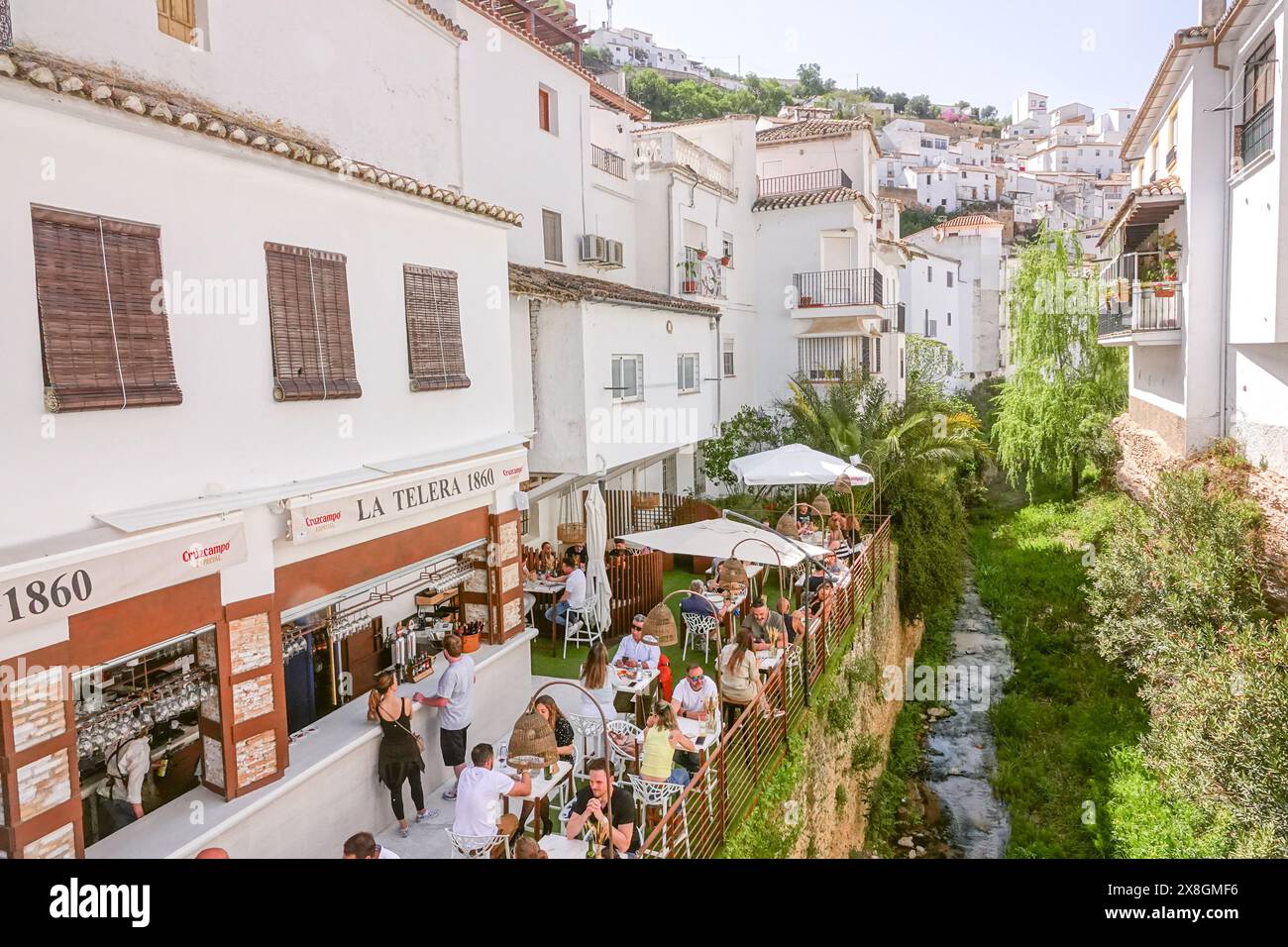 Restaurants and cafes crowd along the Calle Cuevas de la Sombra on the Trejo River n the unique pueblos blanco of Setenil de las Bodegas, Spain. Residents of the tiny village of Setenil have lived in cave houses since neolithic times. Stock Photo