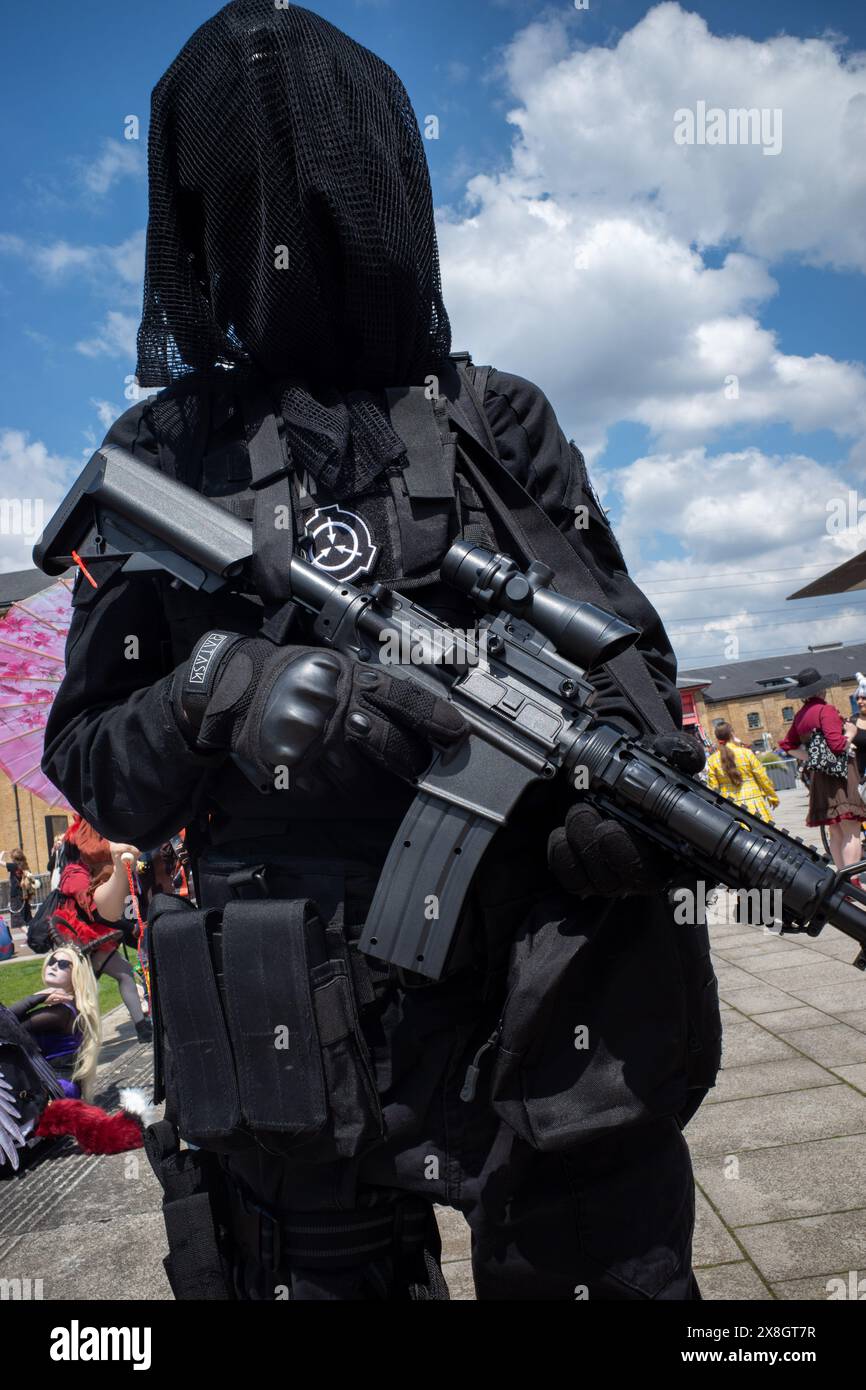 London, UK, 25th May, 2024. A Comic Con character poses with a fake assault rifle. Credit: James Willoughby/Alamy Live News Stock Photo