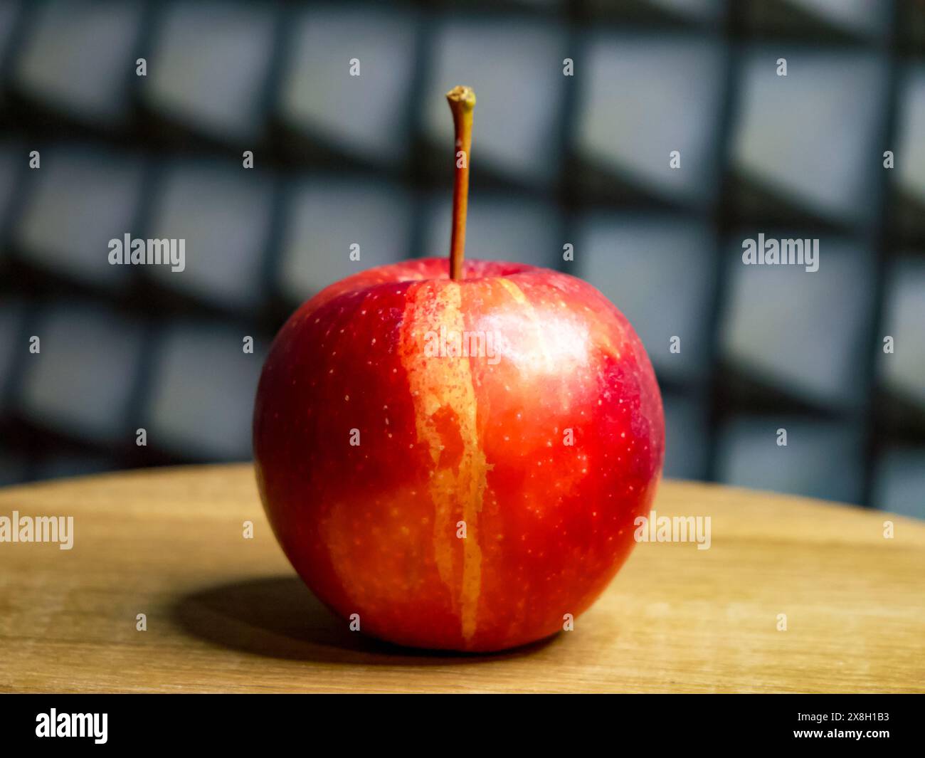 Juicy apple on wood, indicating freshness with water droplets, grey patterned background. Stock Photo