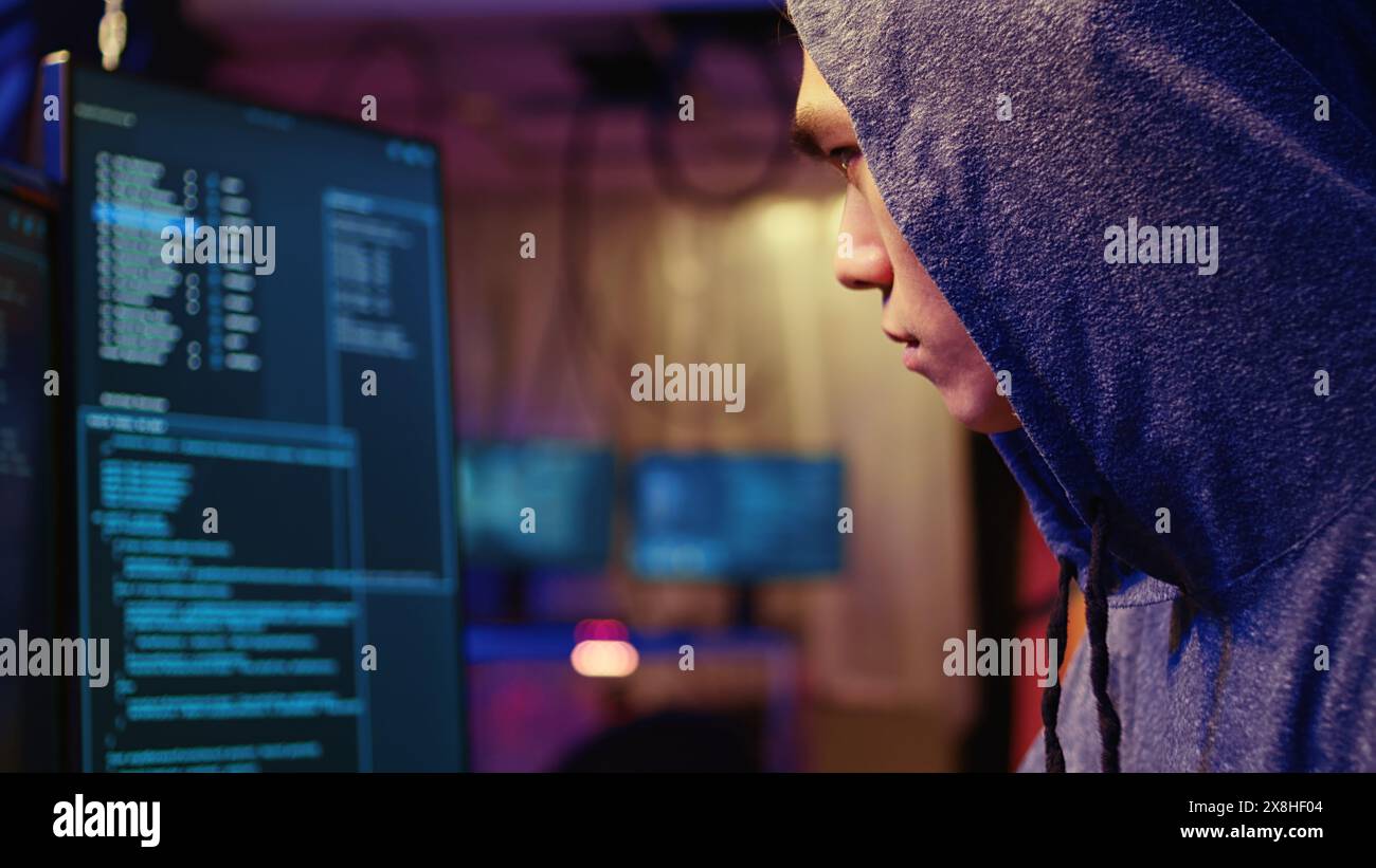 Extreme close up on hacker in graffiti painted hideout focused on developing spyware software, using it to gather information from users computers without their knowledge Stock Photo