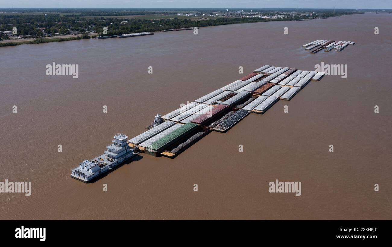 A towboat, known as a pusher, pushes barges full of cargo up the Mississippi River near downtown Baton Rouge, Louisiana, USA. Stock Photo