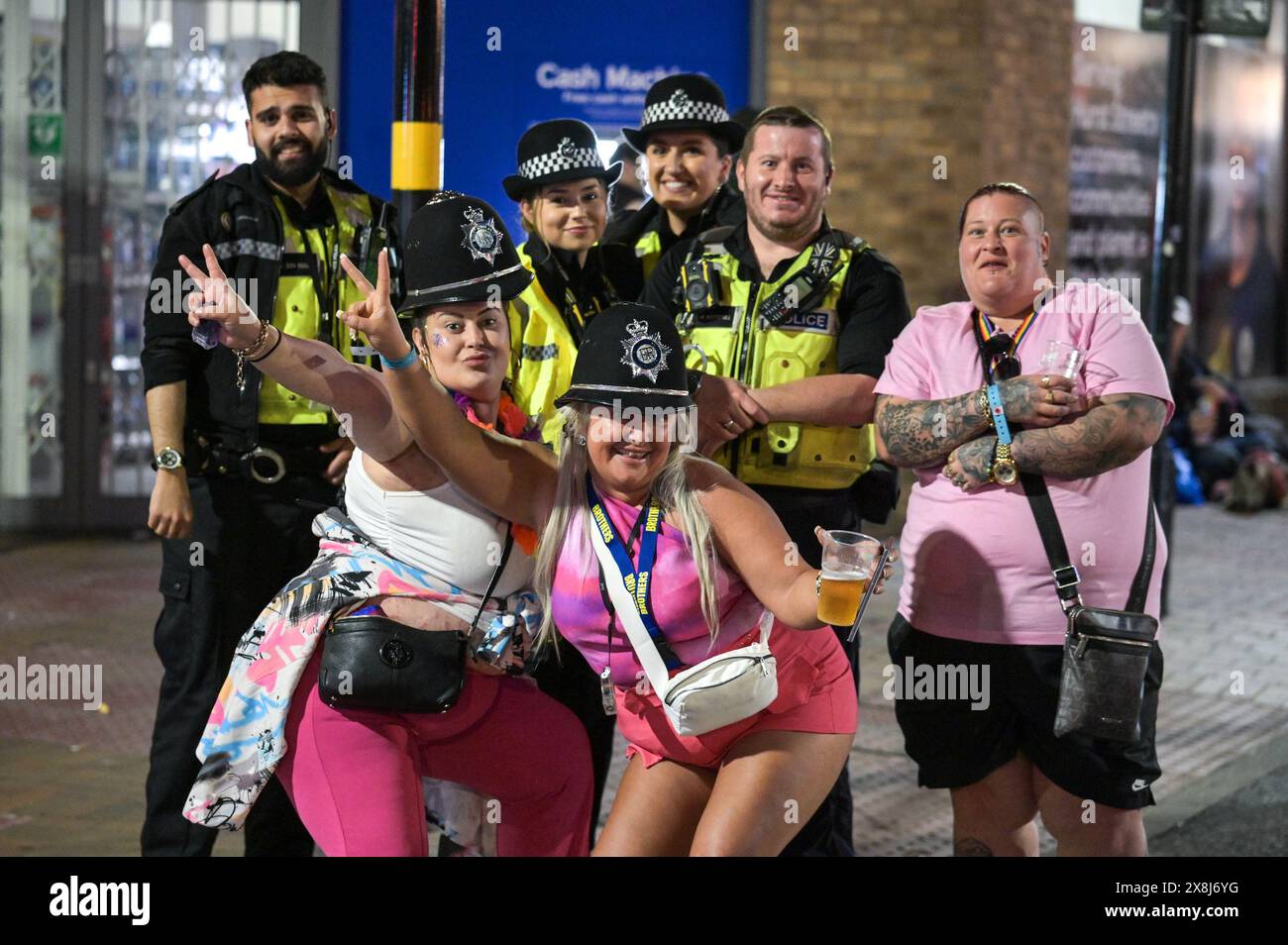 Broad Street, Birmingham, May 26th 2024 - Rain failed to dampen spirits as thousands of revellers took to Birmingham's Broad Street and the Gay Quarter on Saturday night as the Bank Holiday celebrations continued. The partygoers hit the strip packing out Rosies and Heidi's nightclubs. Several revellers were also spotted making their way home from the city's Pride event, with a group of girls in pink posing with some police officers. Credit: Stop Press Media/Alamy Live News Stock Photo