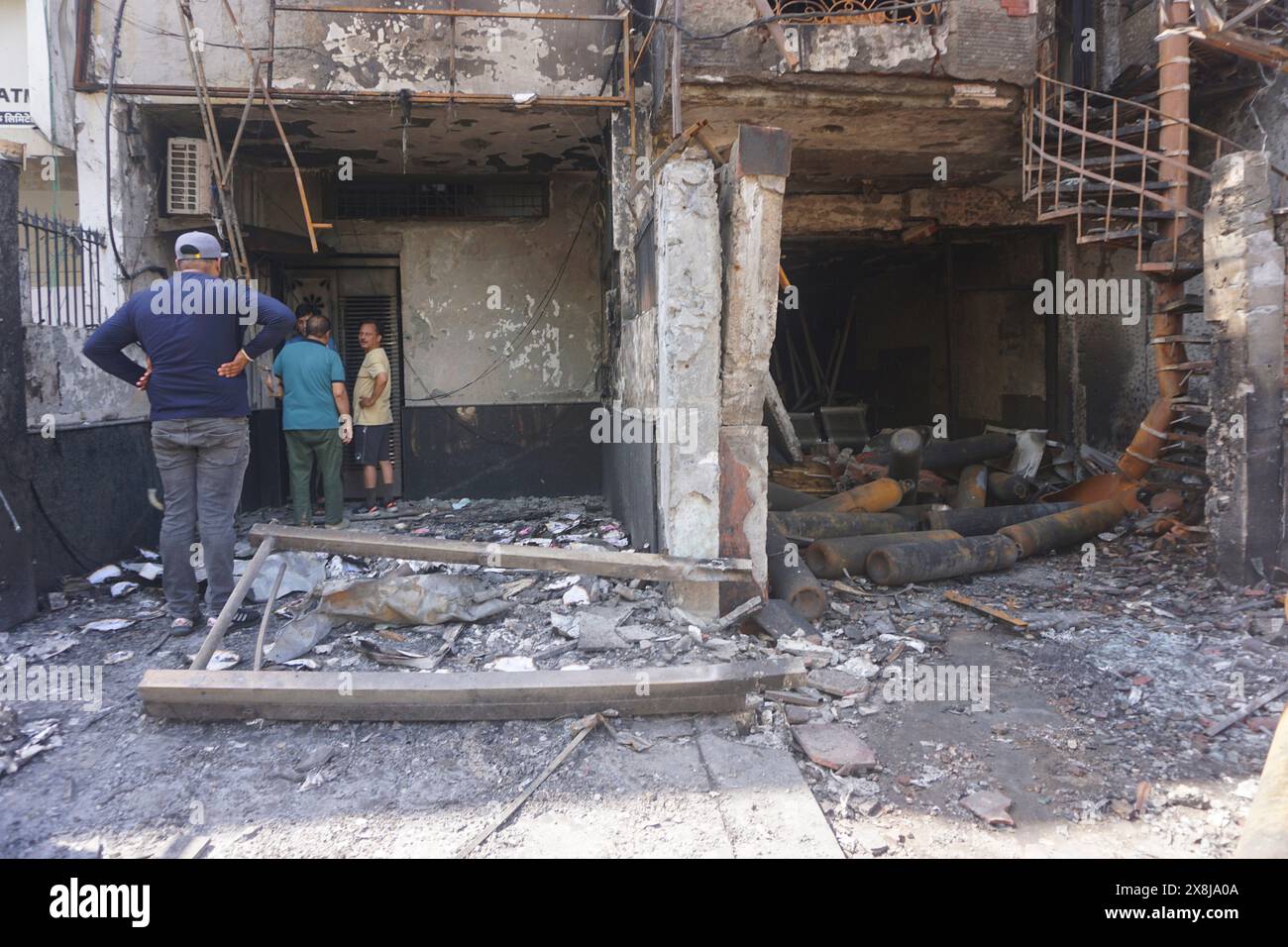 People look at the burnt building of a baby care center in New Delhi, India, Sunday, May 26, 2024. A fire broke out in the care center on Saturday night killing six infants, a fire service officer said on Sunday. (AP Photo/Dinesh Joshi) Stock Photo