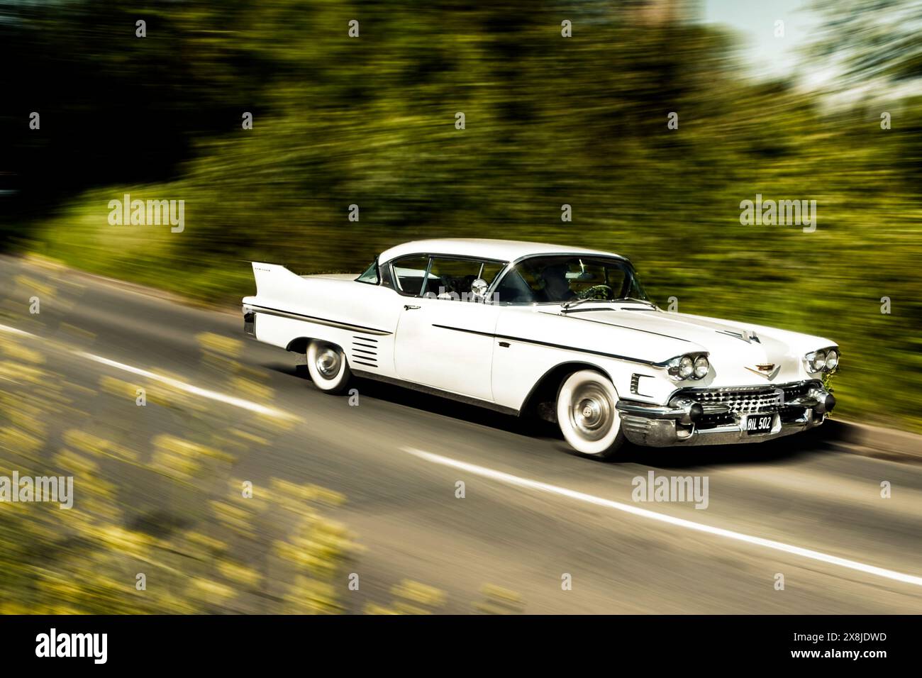 1958 Cadillac Series 62 Coupe De Ville driving at speed on a country road in UK Stock Photo