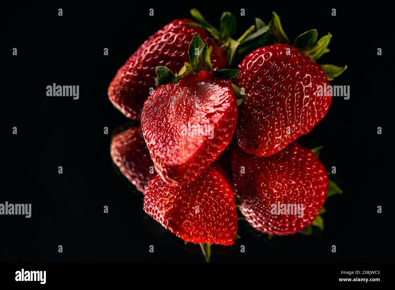 A group of strawberries with a mirror reflection on a black background ...
